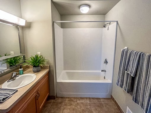 Full bathroom with shower/tub combo, wood cabinetry, and tile floor