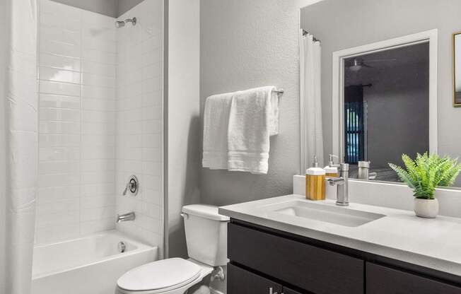 A white towel hangs on a wall above a white sink in a bathroom.