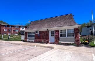 a small brick leasing office with a parking lot in front of it