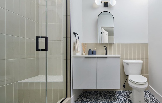 A white toilet sits next to a white cabinet with a mirror above it.