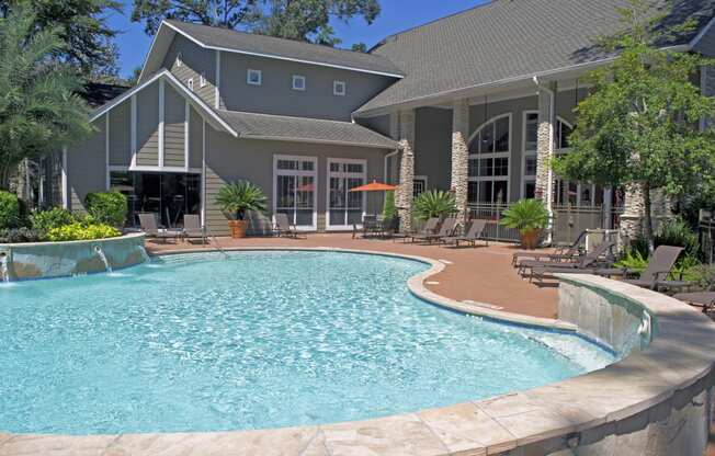 The Woodlands TX Apartments for Rent - Whispering Pines Ranch - Resident Swimming Pool With Crystal Clear Water, Lounge Chairs, and Decorative Trees