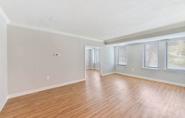 A room with wooden flooring and a window with blinds.