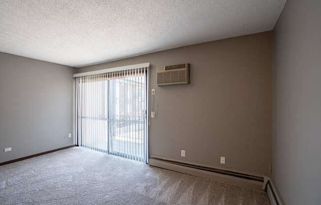 an empty living room with a sliding glass door to a balcony. Roseville, MN Rosedale Estates Apartments