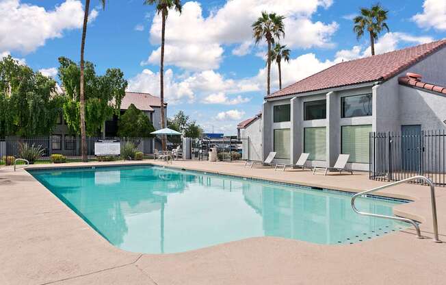 A swimming pool surrounded by palm trees and lounge chairs.