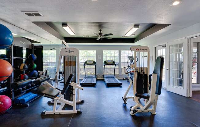 a gym with weights and cardio equipment and windows