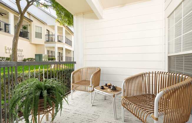 a patio with two chairs and a table in front of a building