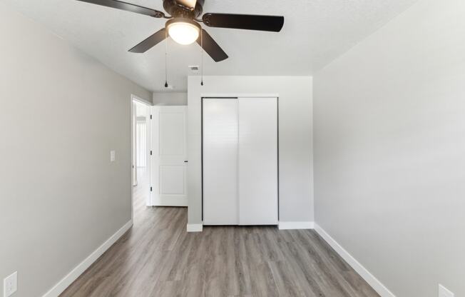 a renovated living room with white walls and a ceiling fan