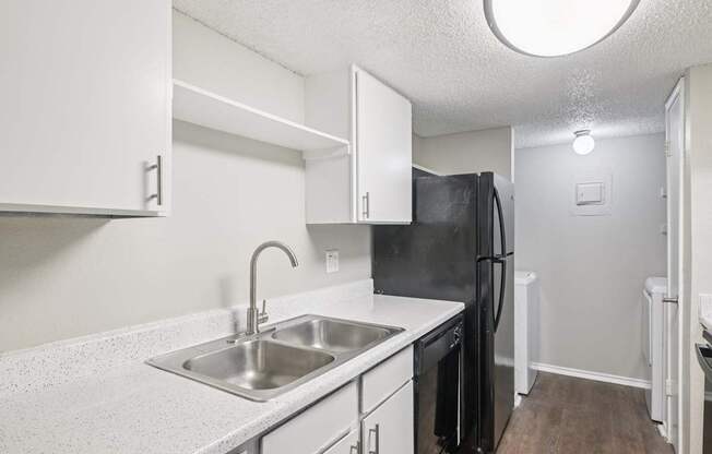 A kitchen with a black fridge and white cabinets.