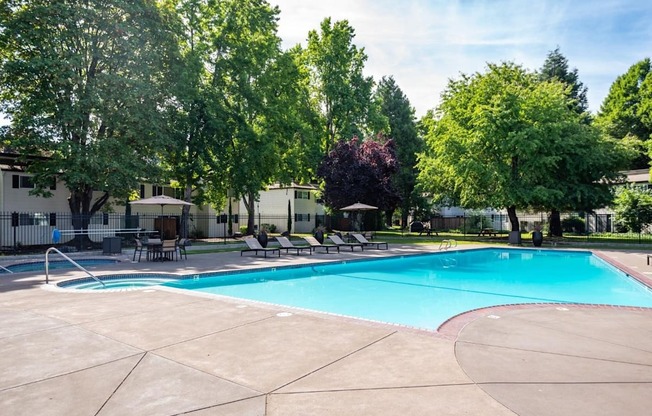 A large swimming pool surrounded by trees and chairs.