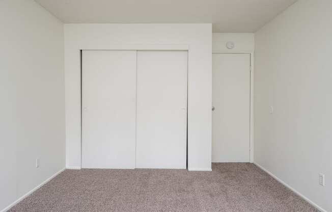 an empty room with a carpet and white closet doors
