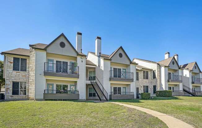 A row of apartments with balconies and staircases leading to the second floor at On the Green apartments in Austin, TX