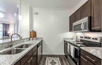 A kitchen with dark brown cabinets and granite countertops.