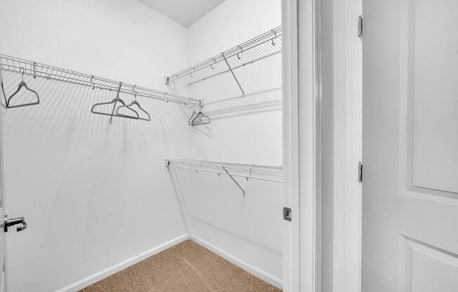 a closet in a bedroom with white walls and hanging racks