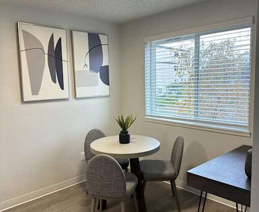 A room with a table, chairs and a plant.