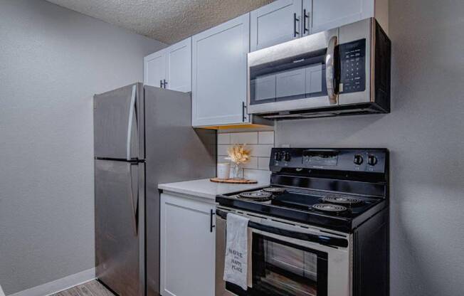 A kitchen with a stainless steel refrigerator, microwave, and oven.