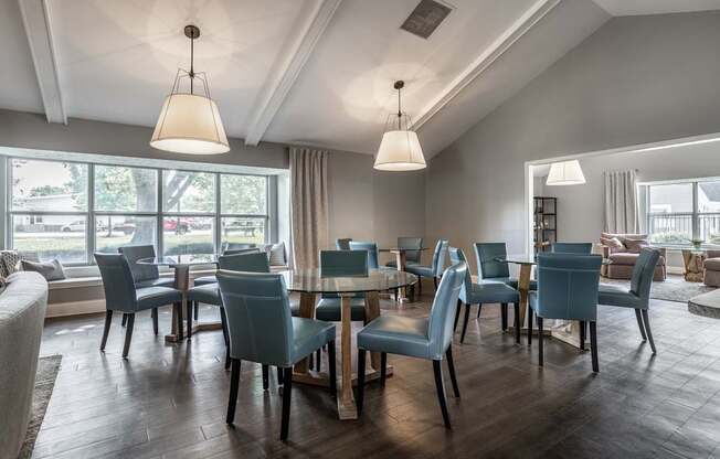 A room with a table and chairs with a window in the background.