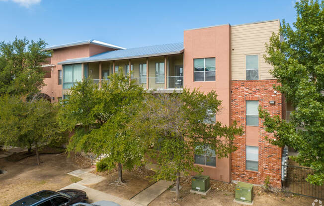 an apartment building with trees and a parking lot