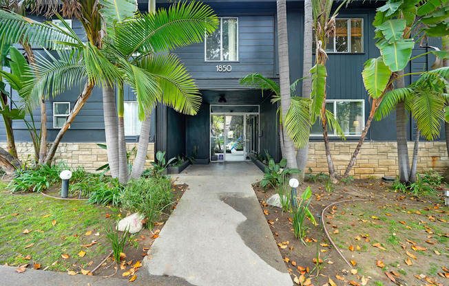 the front of a blue house with palm trees and a walkway