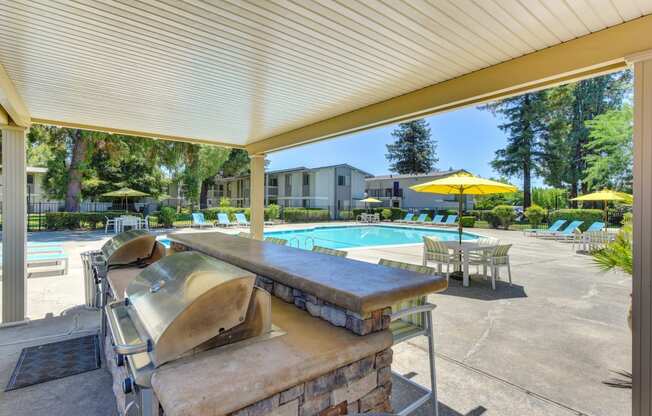 BBQ Area at Pool with Chairs, Tables and Patio Umbrellas at Renaissance Park Apartments, California, 95618