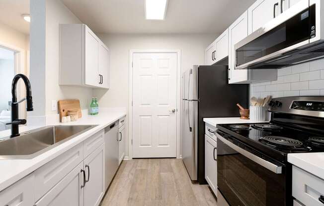 A kitchen with white cabinets and a black stove top oven.