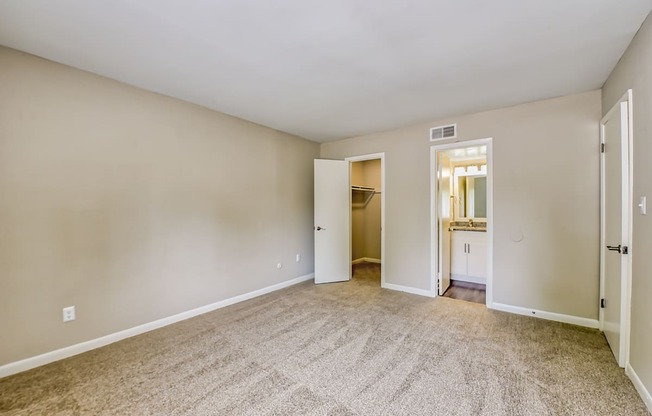 a bedroom with a carpeted floor and an open doorway to a bathroom