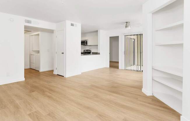 A white room with wooden flooring and a white door.