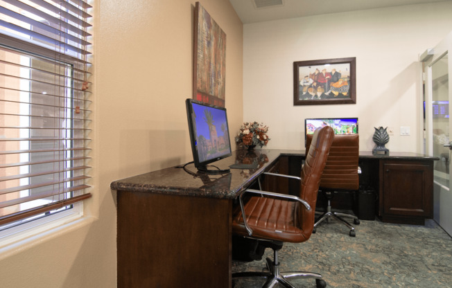 A brown leather chair is in front of a desk with a computer on it.