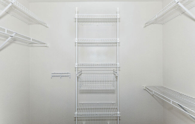 a walk in closet with white walls and white metal shelves