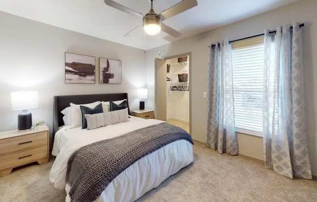a bedroom with a large window and a ceiling fan