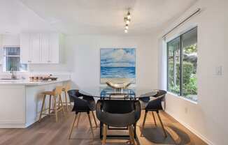 a dining room with a glass table and chairs and a kitchen with a large window