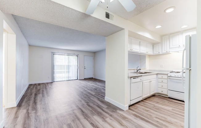 an empty kitchen and living room with a ceiling fan  at Redlands Park Apts, California, 92373