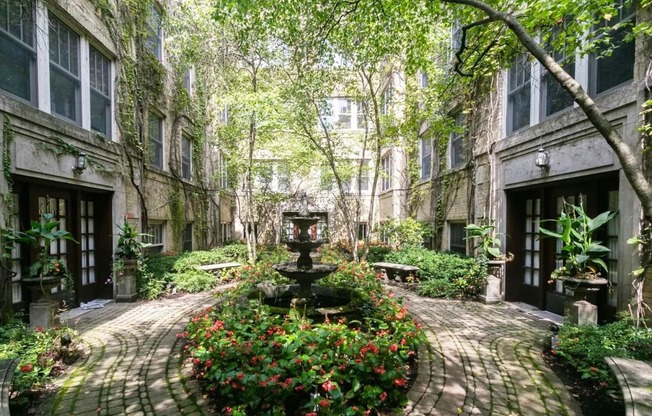 a courtyard with a fountain and flowers in front of a building at The Bryant at Oak Park I & II, Oak Park