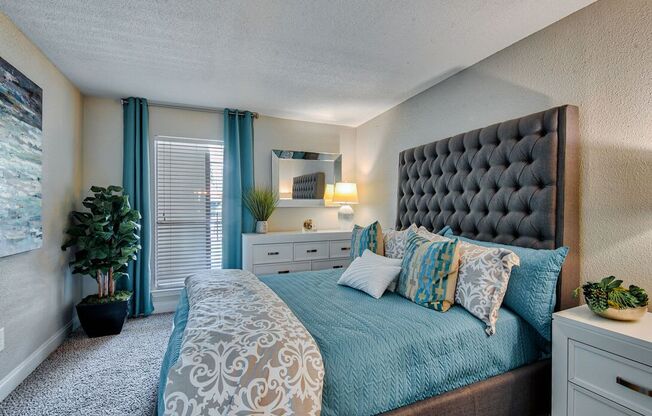 A bedroom with a large bed and a potted plant.