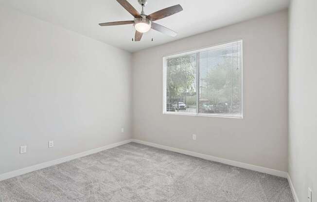 A room with a ceiling fan and a window.