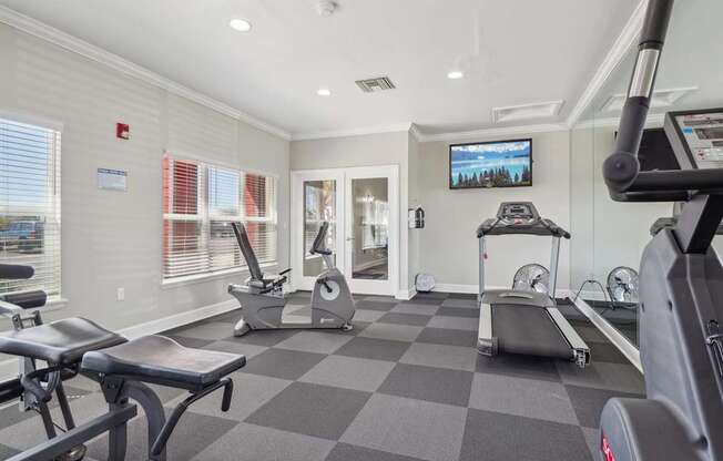 A gym with a variety of equipment including treadmills, stationary bikes, and weight machines.