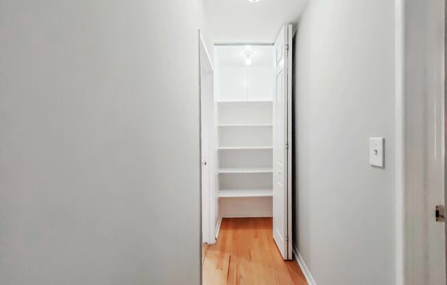 a bedroom with a medium grey wall and a white closet with white shelves