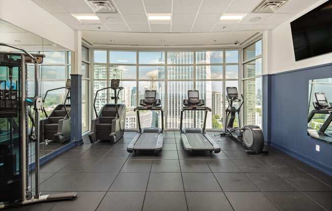 a gym with cardio machines and a view of the city