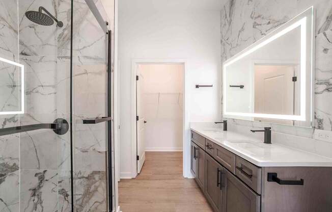 A bathroom with a marble shower and a white sink vanity.