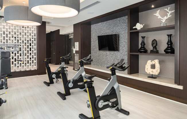 a row of exercise bikes in a fitness center with a tv