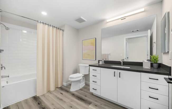 a bathroom with white cabinets and a black countertop