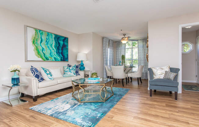 Pet-Friendly Apartments in Stockbridge, GA - Avenue 33 - Living Room with Wood-Inspired Plank Flooring, a Dining Area With a Ceiling Fan, and Windows with Blinds.