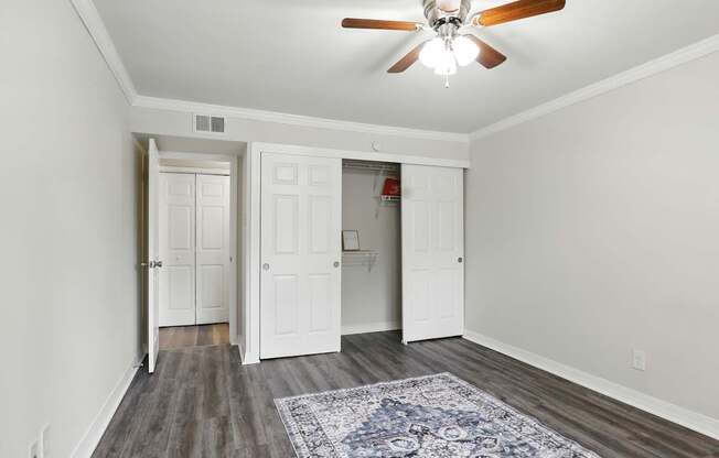 A room with a ceiling fan and a rug on the floor.