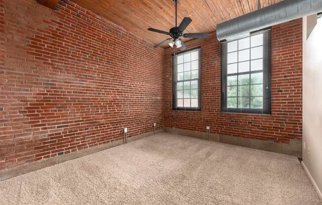 an empty room with a brick wall and a ceiling fan