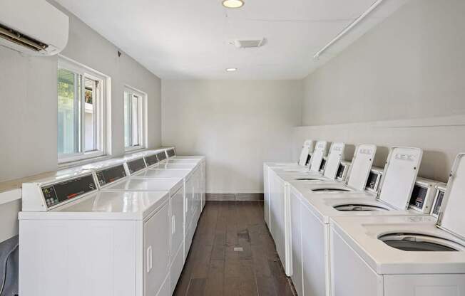 A row of white washing machines in a laundromat.