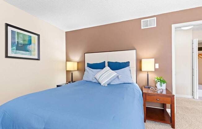 A bed with a blue cover and two blue pillows is in the image.