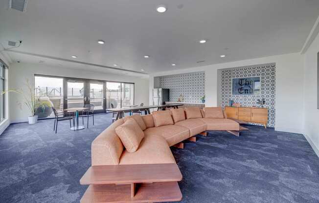 A long wooden table with a bench in front of a grey carpet.