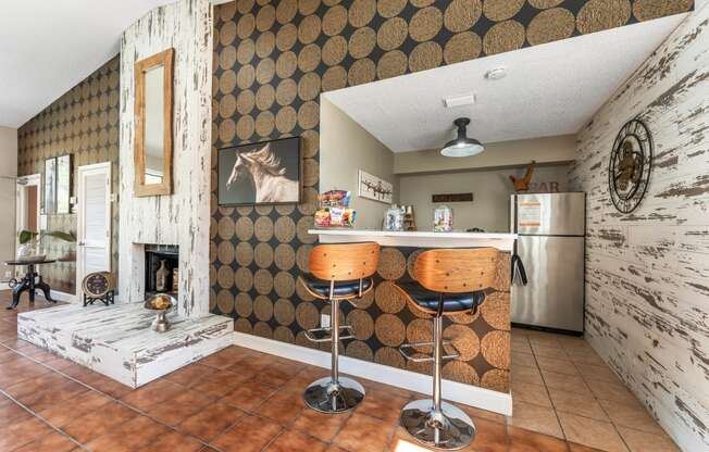 a kitchen with a bar with two stools and a fireplace