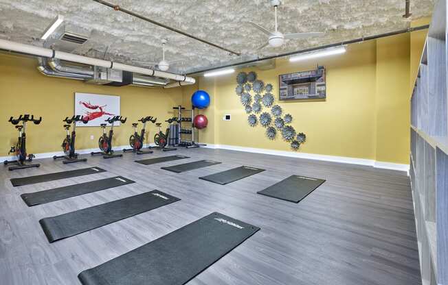 a yoga room with yoga mats on the floor and a yellow wall with bikes