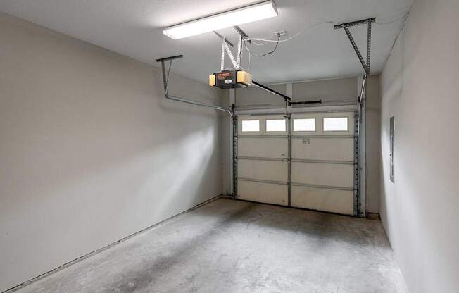 A garage with a white wall and a grey floor.