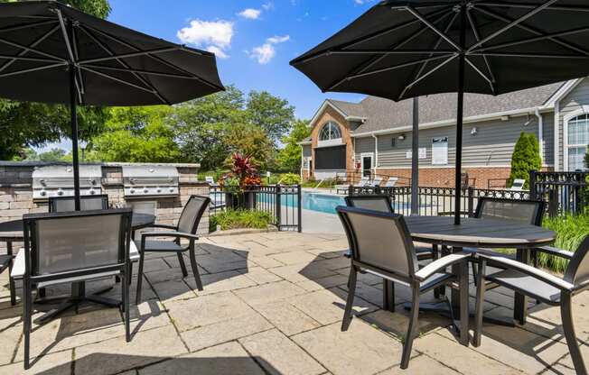 a patio with tables and umbrellas next to a swimming pool